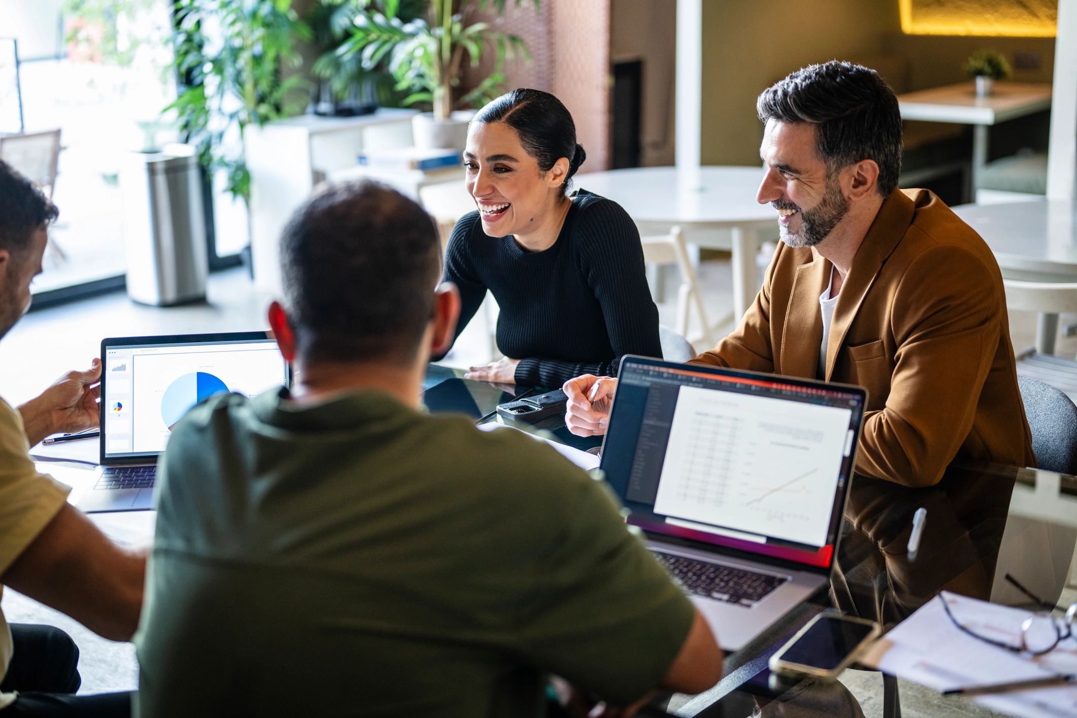 Technology consultants collaborating around laptops in a business meeting